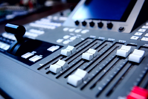 Close-up of an audio mixing console with sliders and control knobs.