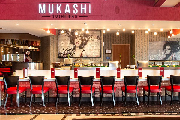 A sushi bar with red chairs lined along a counter