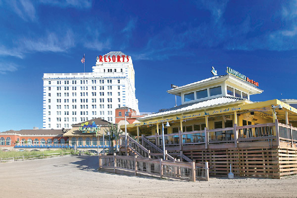 Beachfront restaurant with wooden deck and a large hotel in the background.