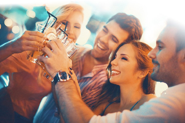 several smiling people bring their glasses together in a toast