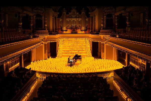 A stage showing a piano player surrounded by hundreds of candles.