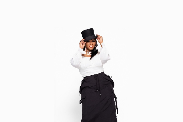 Promotional image of a performer in a black top hat and black-and-white outfit, posing against a white background.